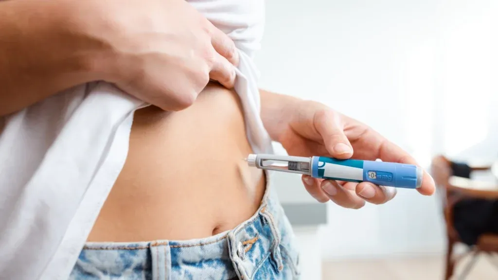 A patient giving an injection pen under the skin of the abdomen