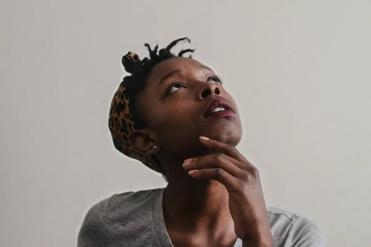 A woman with her hand under her chin, looking up
